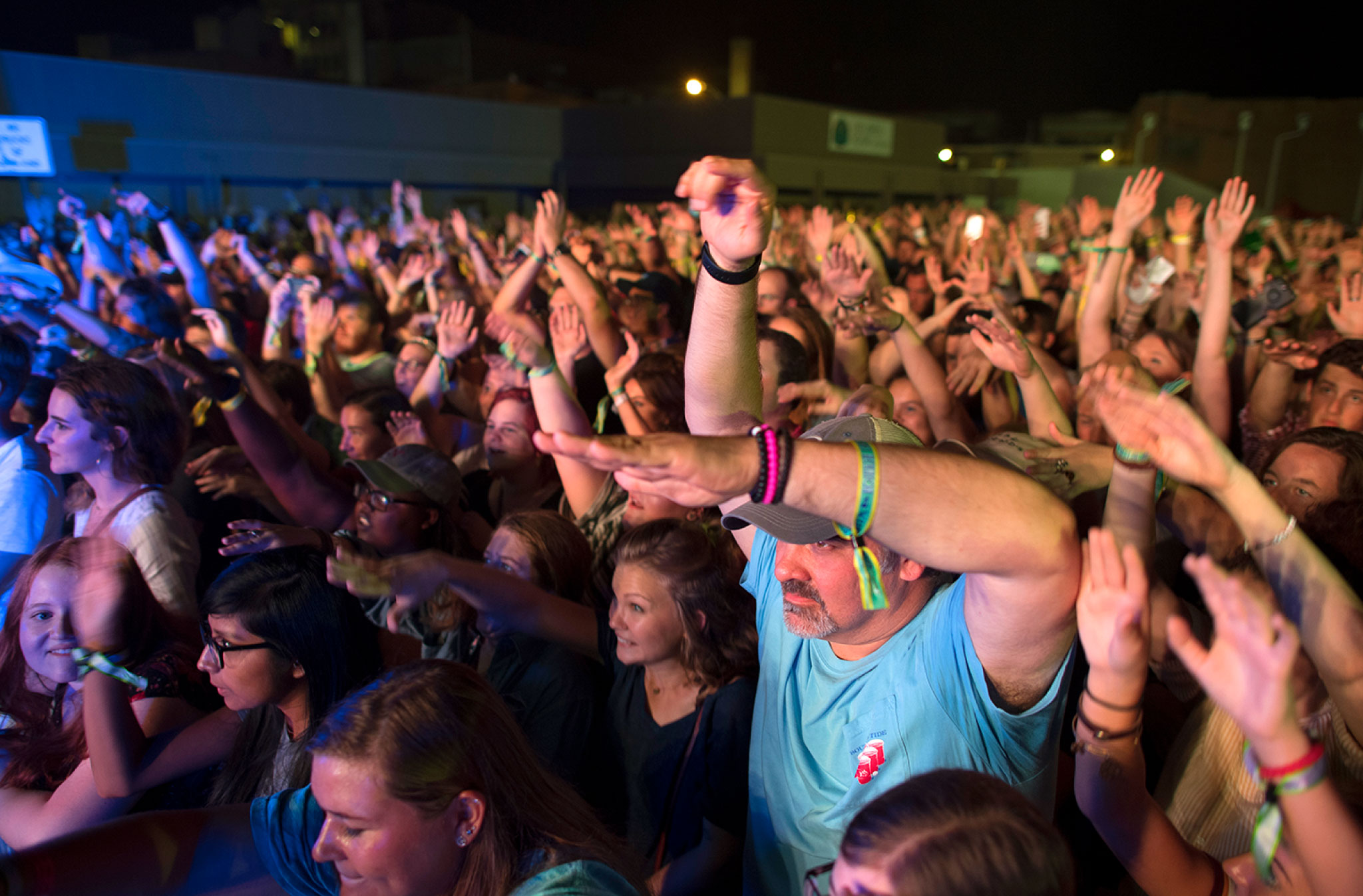 A full crowd is seen, pumping their hands to the music, looks of excitement and energy on their faces.