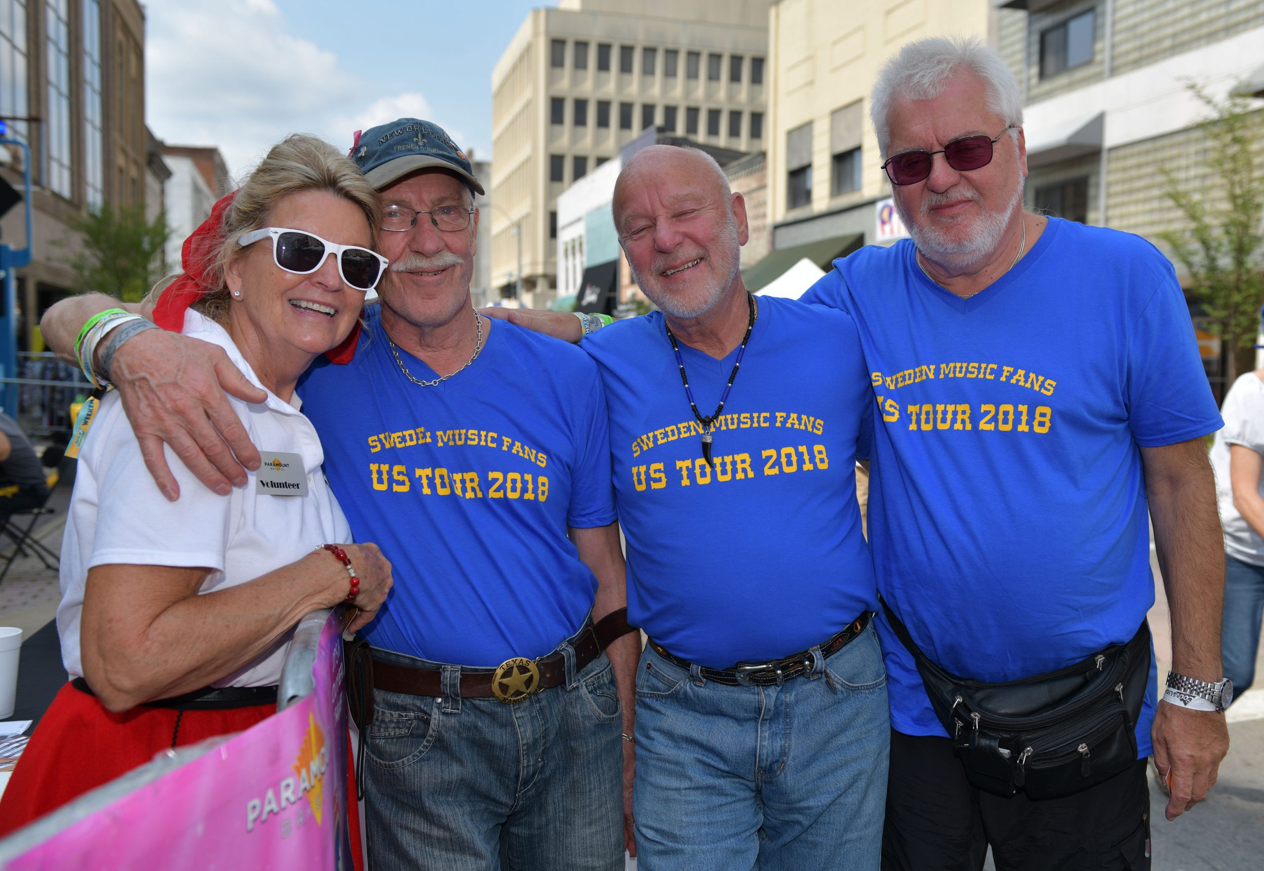 A group of three men and one woman, the men wearing matching t-shirts that read "Swedish Music Fans US Tour 2018."
