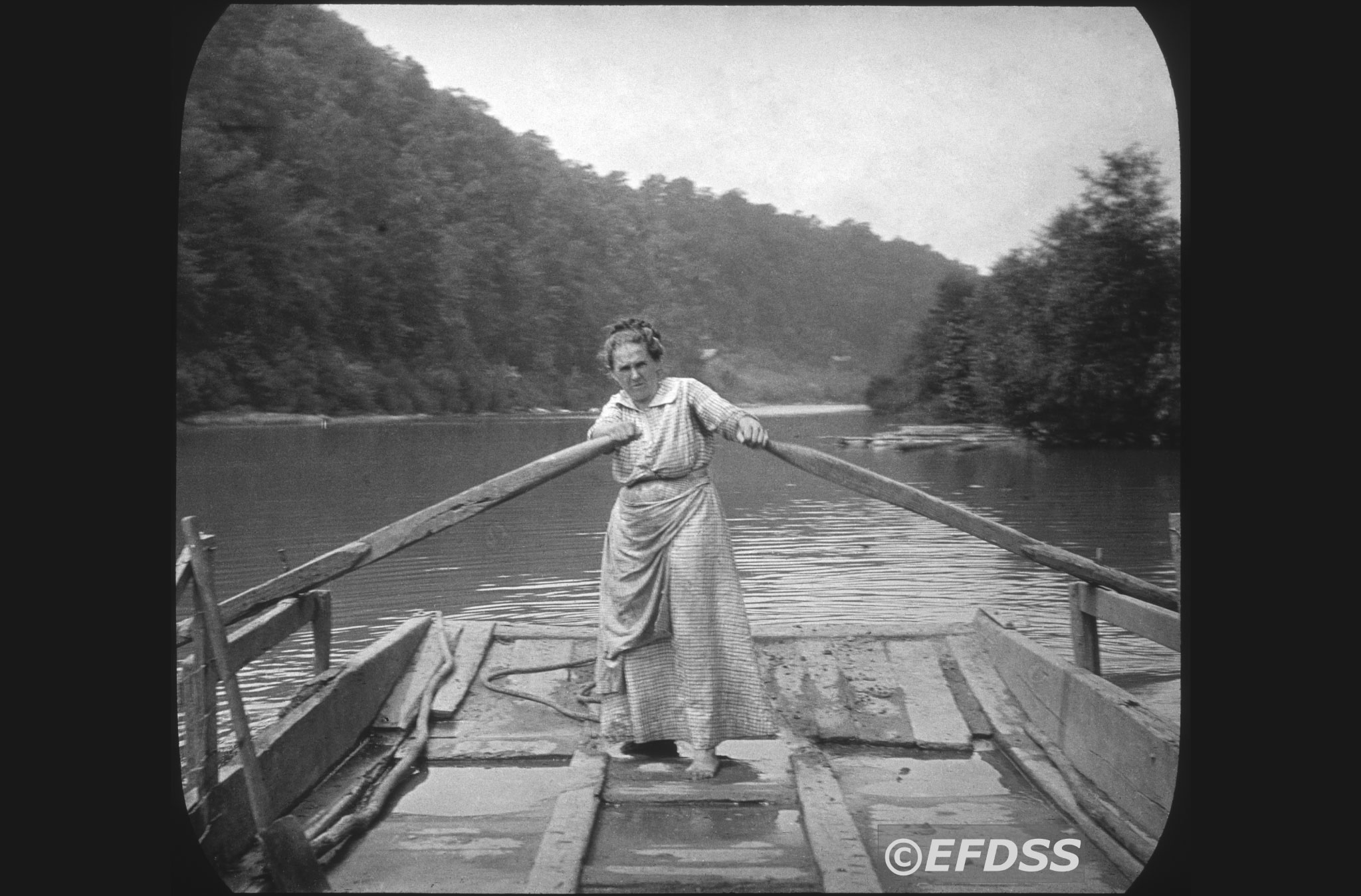 Black and white photo of a woman rowing a barge