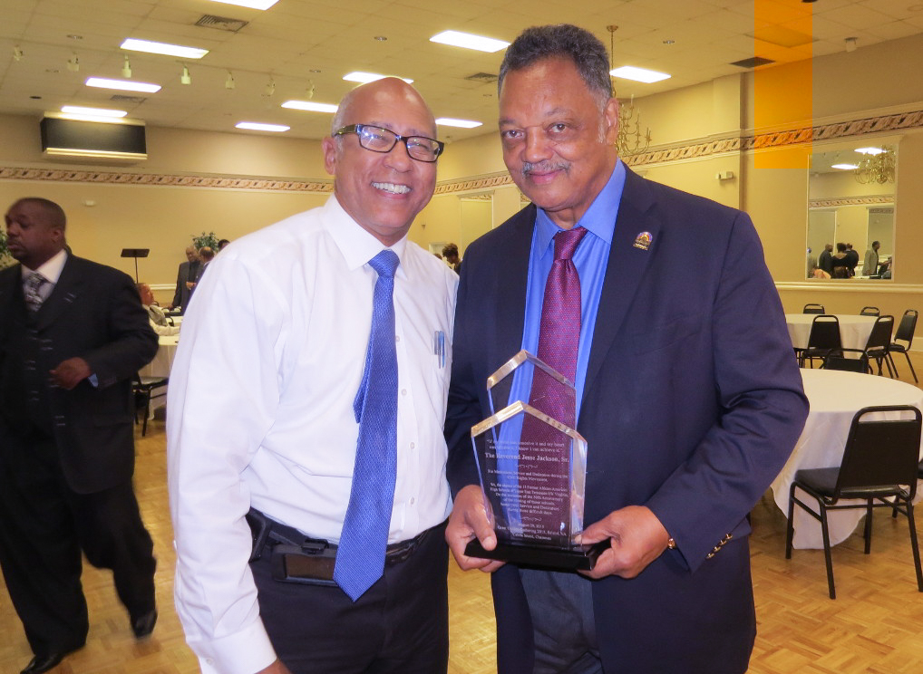 Calvin Sneed poses with the Reverend Jesse Jackson, who holds a clear plaque honorarium.