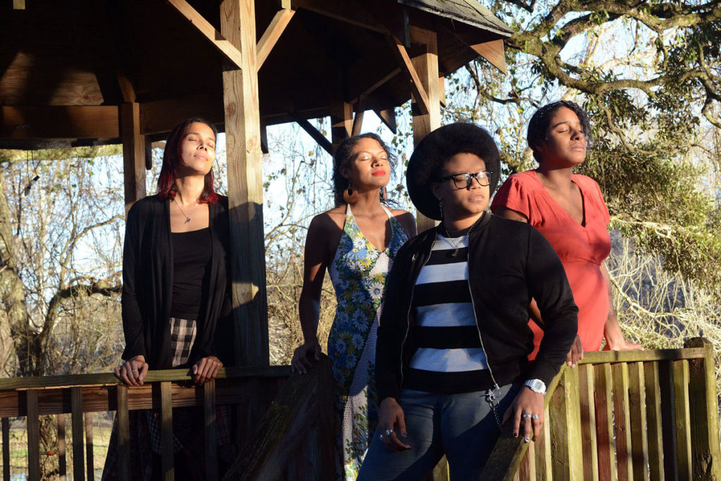 Album promotional photograph showing the four musicians on a cabin porch, faces to the sun and eyes closed.
