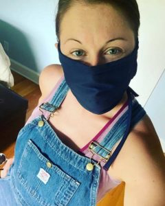 Beth Snapp in overalls wearing a dark blue denim face mask.