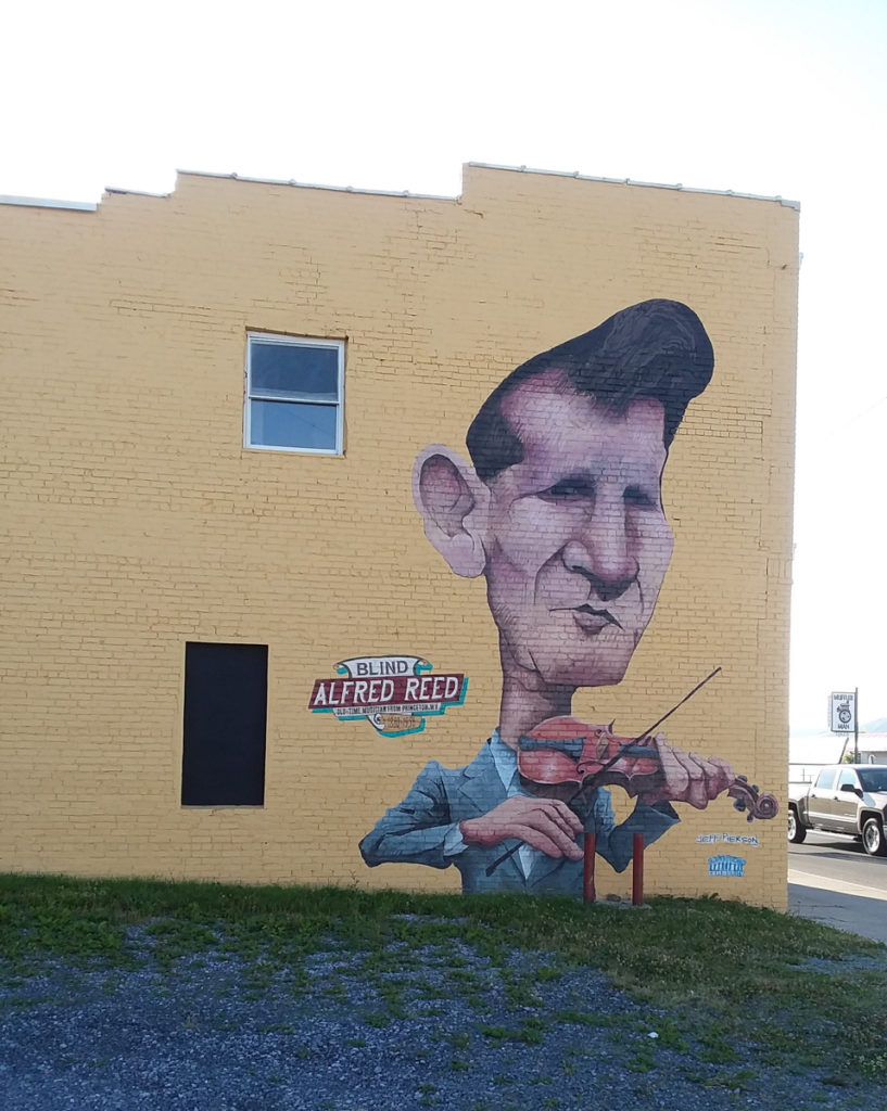 Large building with a caricature-like portrait of Blind Alfred Reed playing his fiddle on one side.