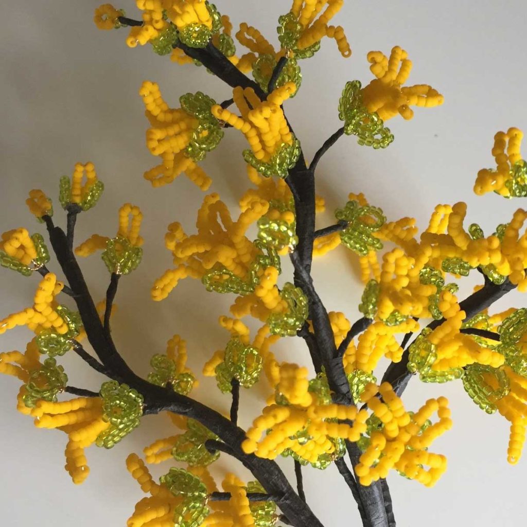 Honeysuckle flowers made from intricate yellow and green beads.