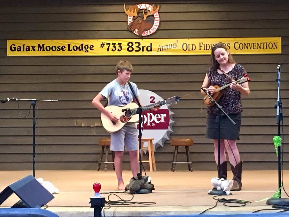 Two youth musicians on stage -- the one to the left on guitar, the one to the right on mandolin.