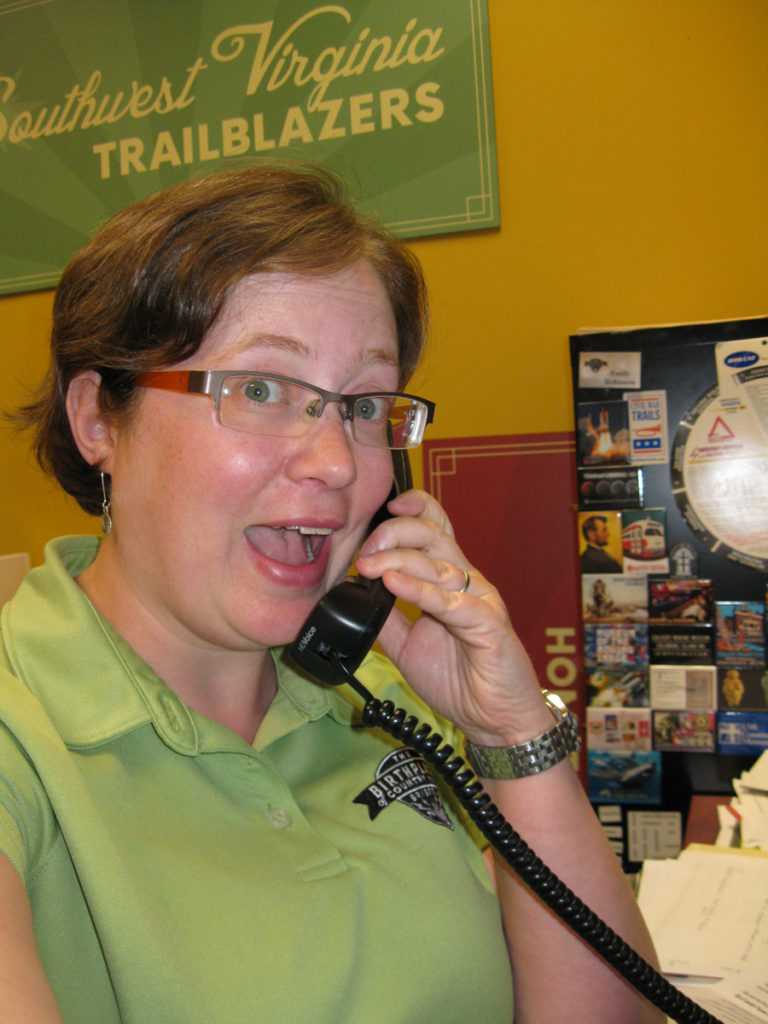 Photograph of Collections Manager Emily Robinson answering the phone and looking excited!