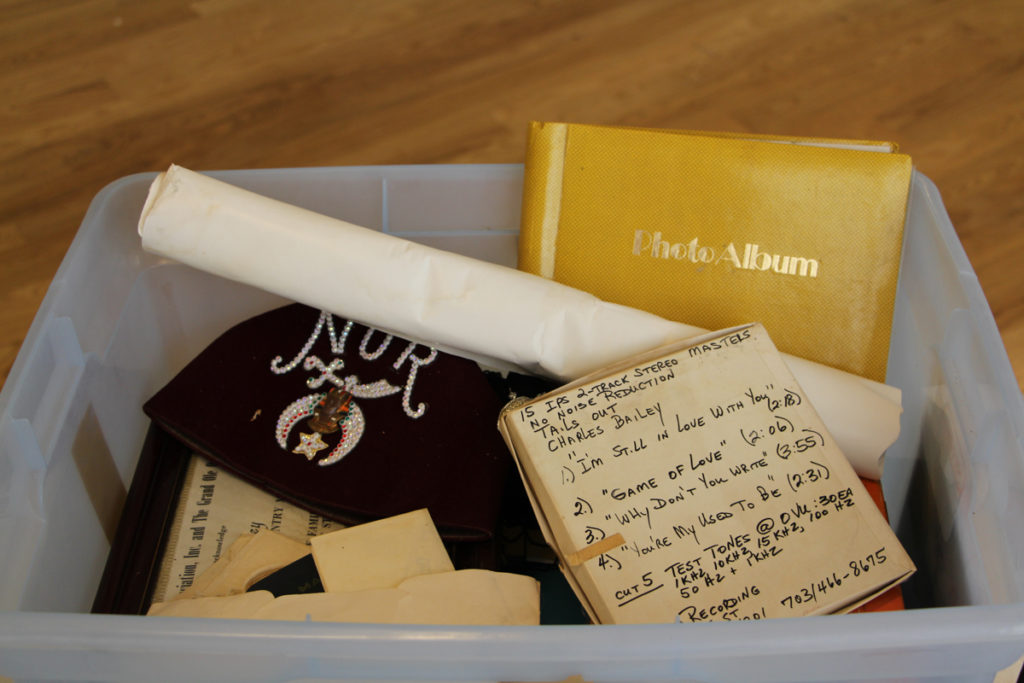 Photograph of a plastic tote filled with items from the Bailey Collection, including a photo album, various paper items, audio tapes, etc.