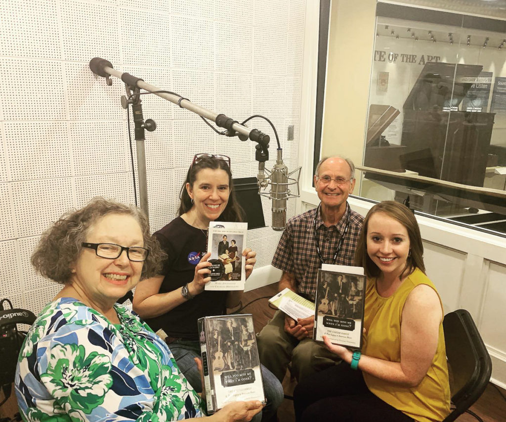 The four readers for the July 2019 book club are pictured around the Radio  Bristol studio mic; three readers are holding the book up.