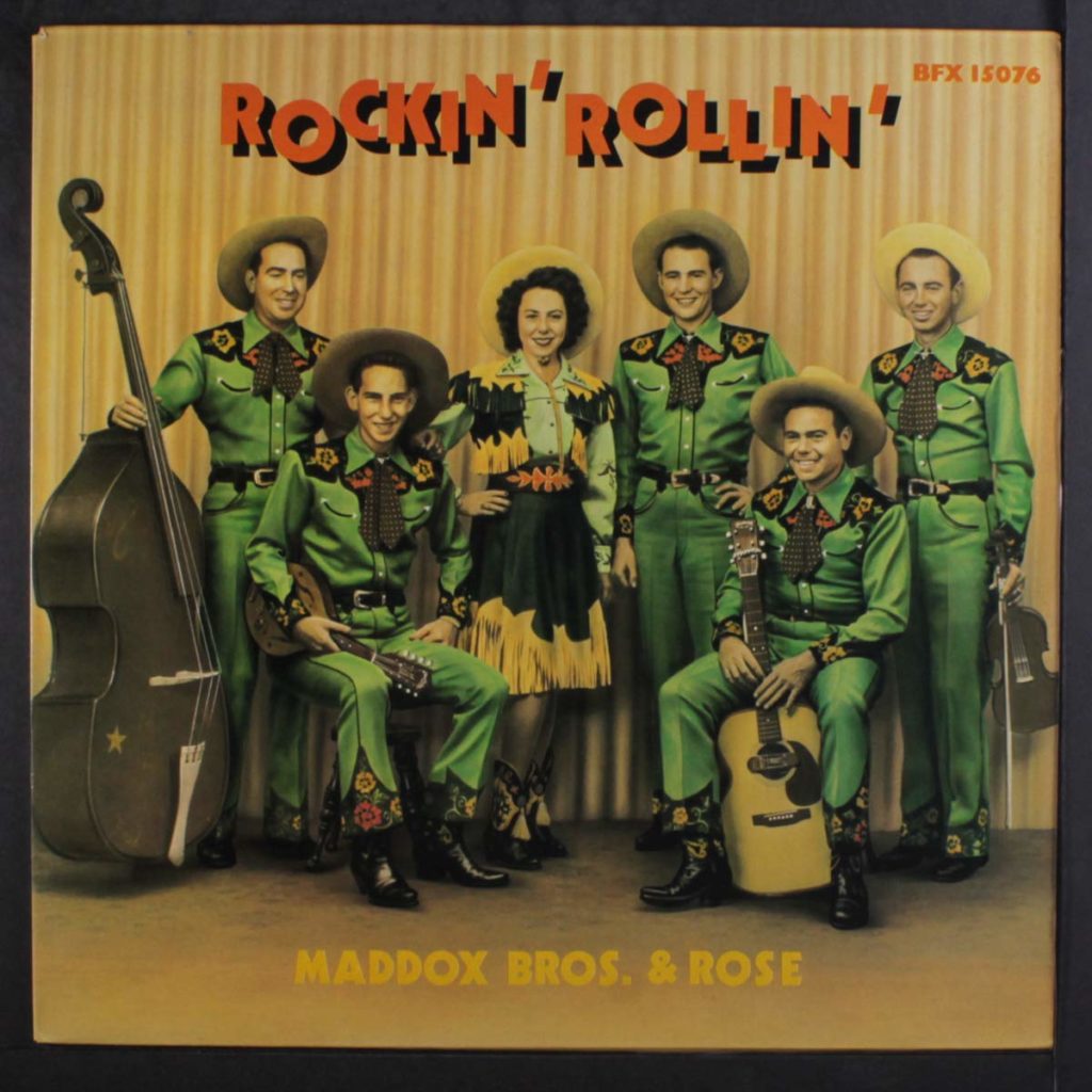 The Rockin' Rollin' album cover for the Maddox Brothers & Rose shows all of the male band members in green, highly decorated suits and cowboy hats, with Rose in a matching cowgirl-style outfits covered in fringe and beadwork.