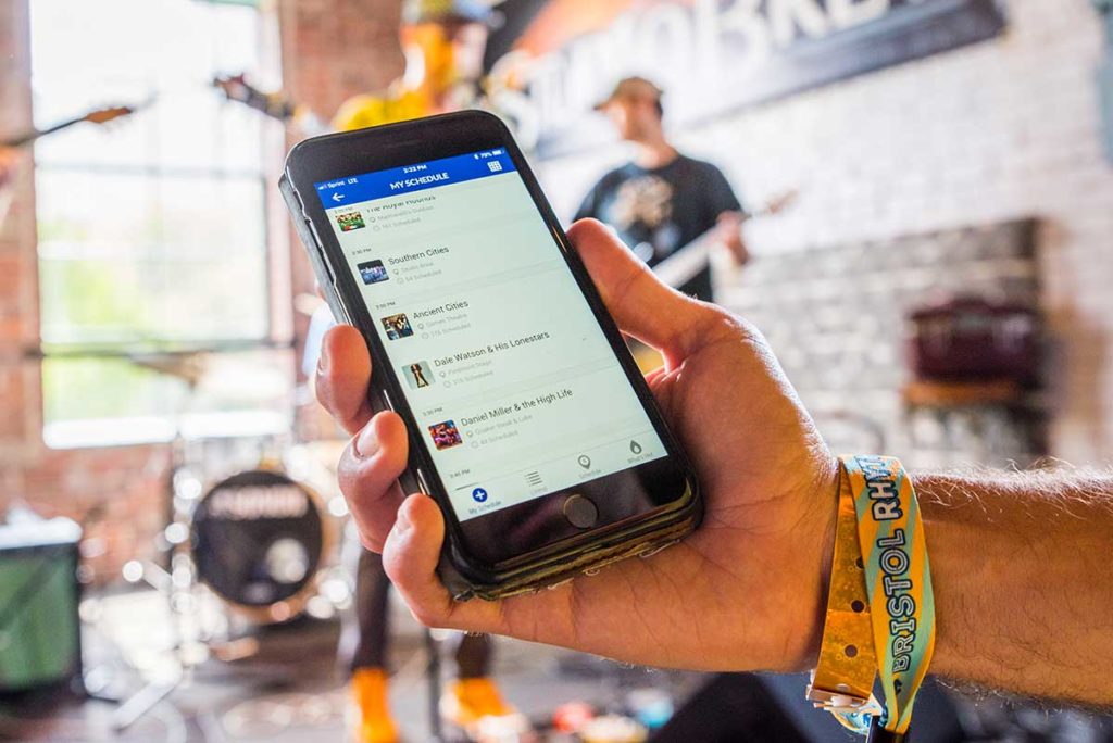 Photo of a hand holding a smartphone with the Bristol Rhythm & Roots Reunion mobile app.