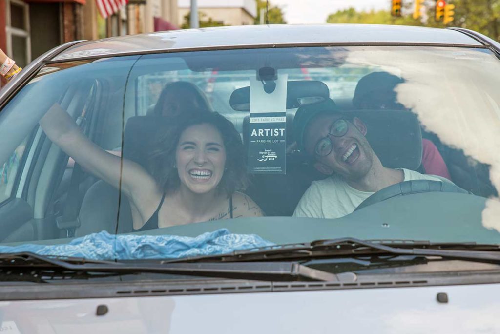 Photo of smiling people inside a car.