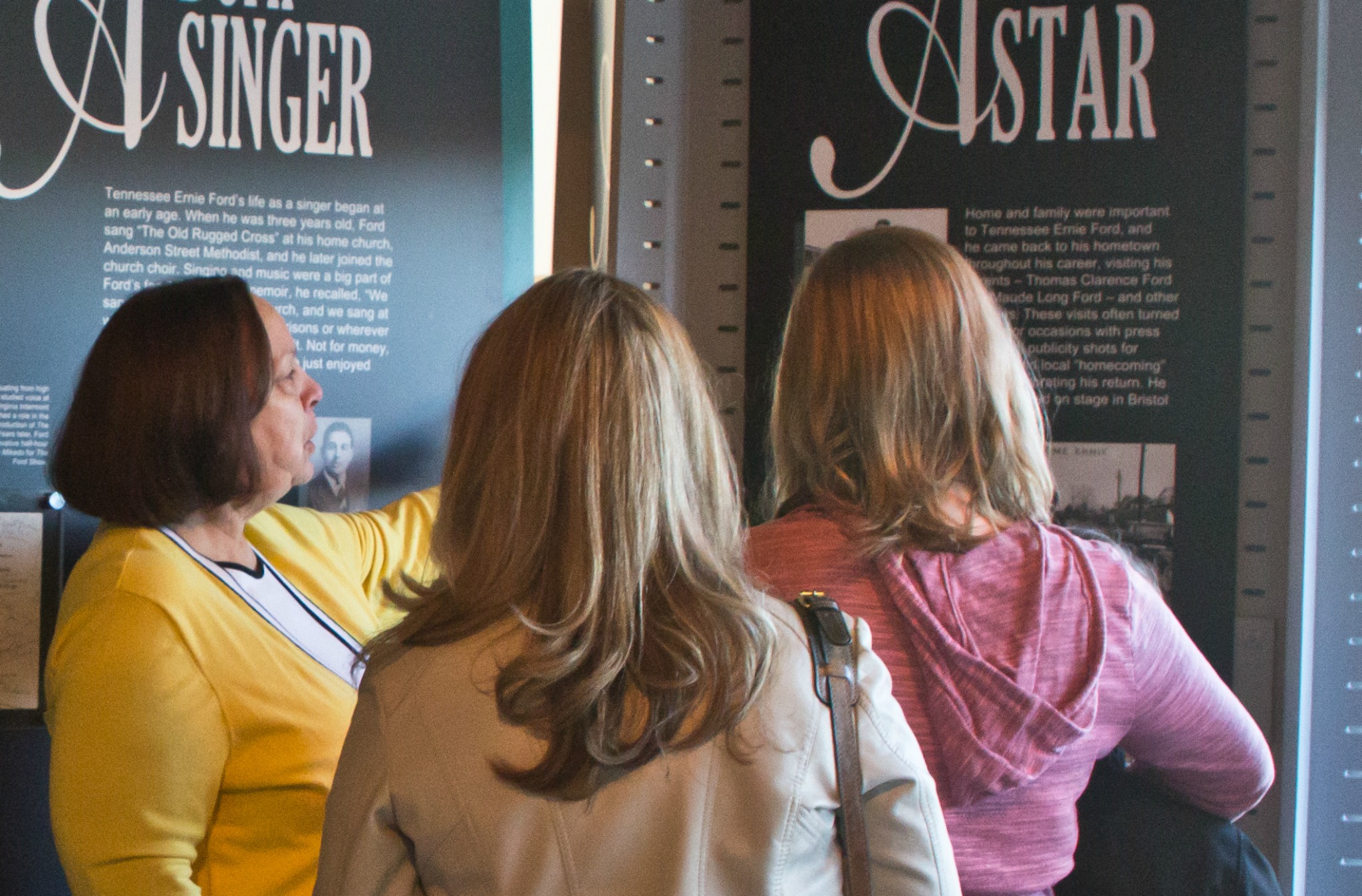 Photo of a volunteer showing two female visitors our temporary Tennessee Ernie Ford exhibit in 2015