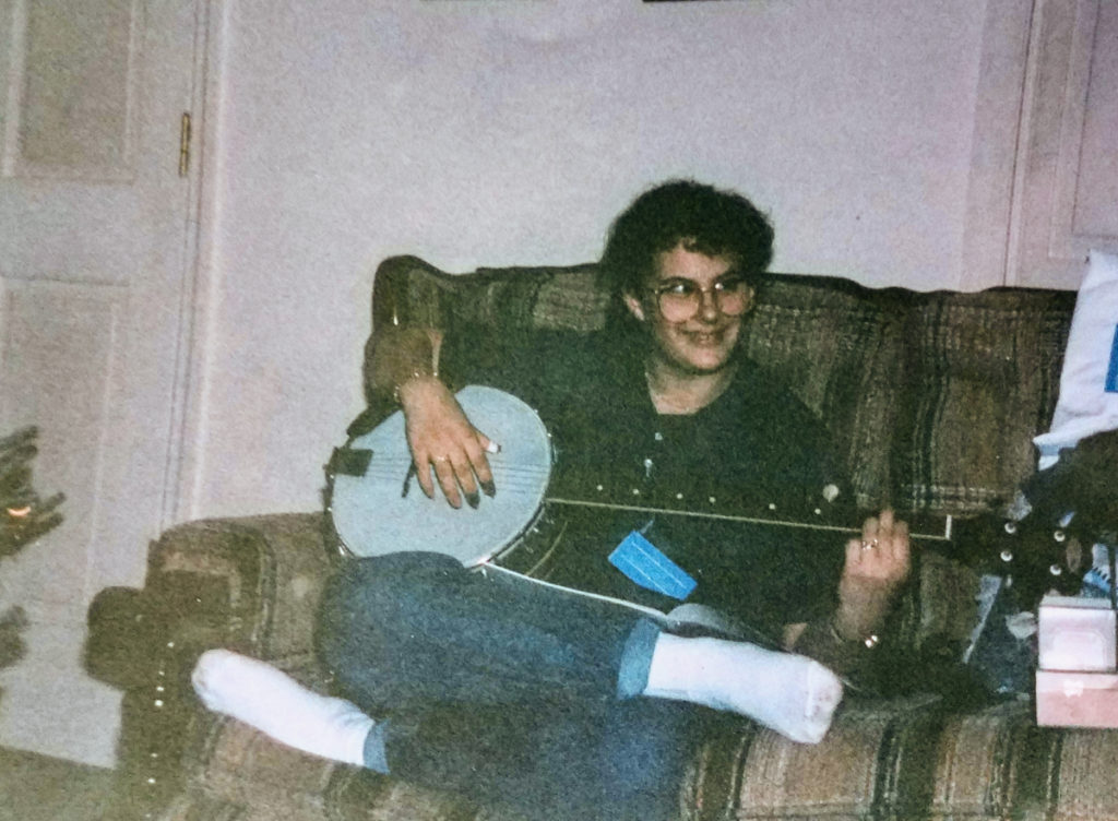 A teenage Trish Fore sitting on her couch holding her new banjo.