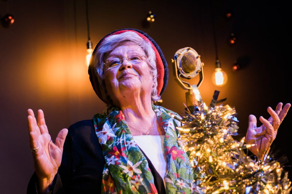 Judy "Butterfly" Farlow in front of the Christmas mic sharing her story of childhood biscuits.