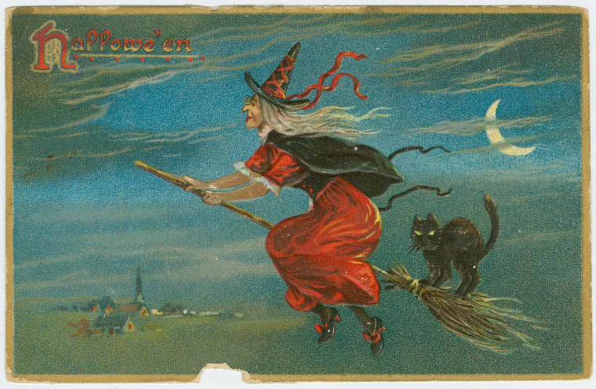 Old Halloween postcard of a witch in a red dress riding a broomstick with a black cat on the back.