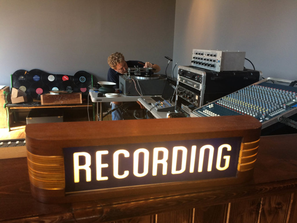 A large lit up sign reading "Recording" in front of the recording equipment at The Earnest Tube.