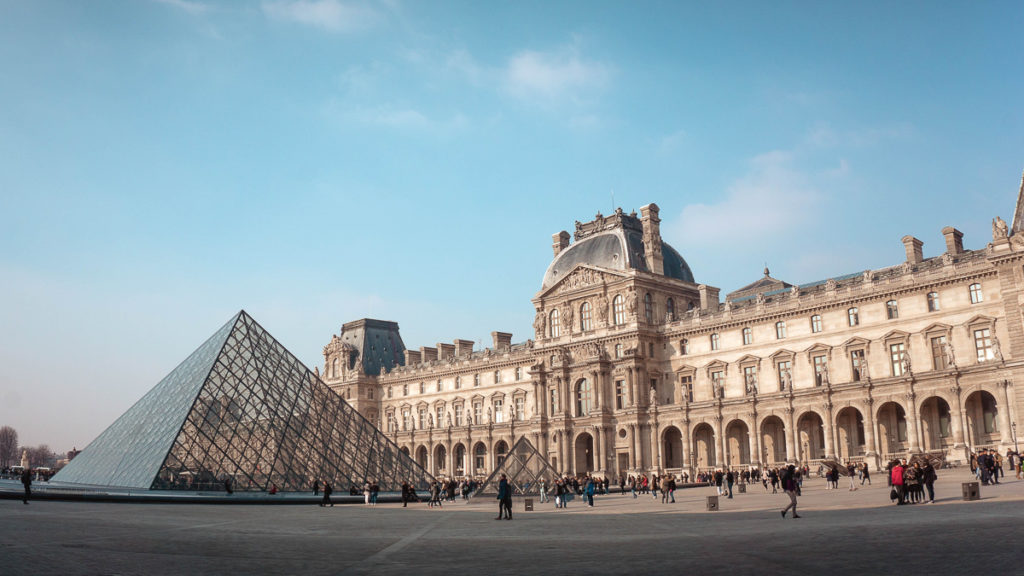 A picture of the Louvre's front facade with the glass pyramid Louvre extension in front of it.