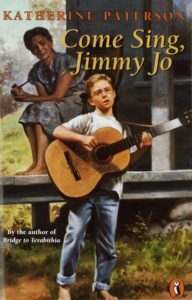 Book cover shows a young white boy with light hair and glasses singing and playing guitar in the front yard of a wooden house. He is wearing a t-shirt and jeans. Behind him, an older gray-haired woman sits on the porch listening to him. She wears a light-colored dress.