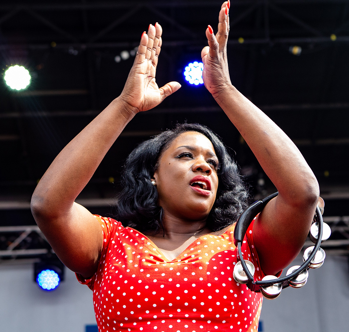 A photo of Tanya Trotter of The War in Treaty from Bristol Rhythm 2018. Her hands are in the air above her head and she appears to be clapping to the music on stage.