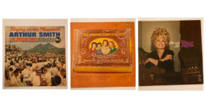 Three album covers from left to right: Arthur Smiths's Singing on the Mountain shows a huge crowd of people gathered together in an open space in the mountains with a mountain peak rising in the distance; center, The Carter Family Album is designed to look like a family photograph album with Mother Maybelle and the Carter Sisters in the center of the album cover; right, the Dolly Parton album has Dolly sitting on a Victorian-style velvet chair or couch, she is wearing a black outfit and her golden blonde hair is piled high on her head as curls.