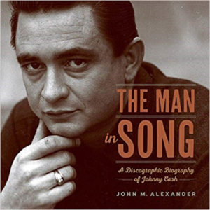The Man in Song book cover shows a black-and-white image of a young-ish Johnny Cash. He is looking straight at the camera, wears all black, and has his chin on his hand.