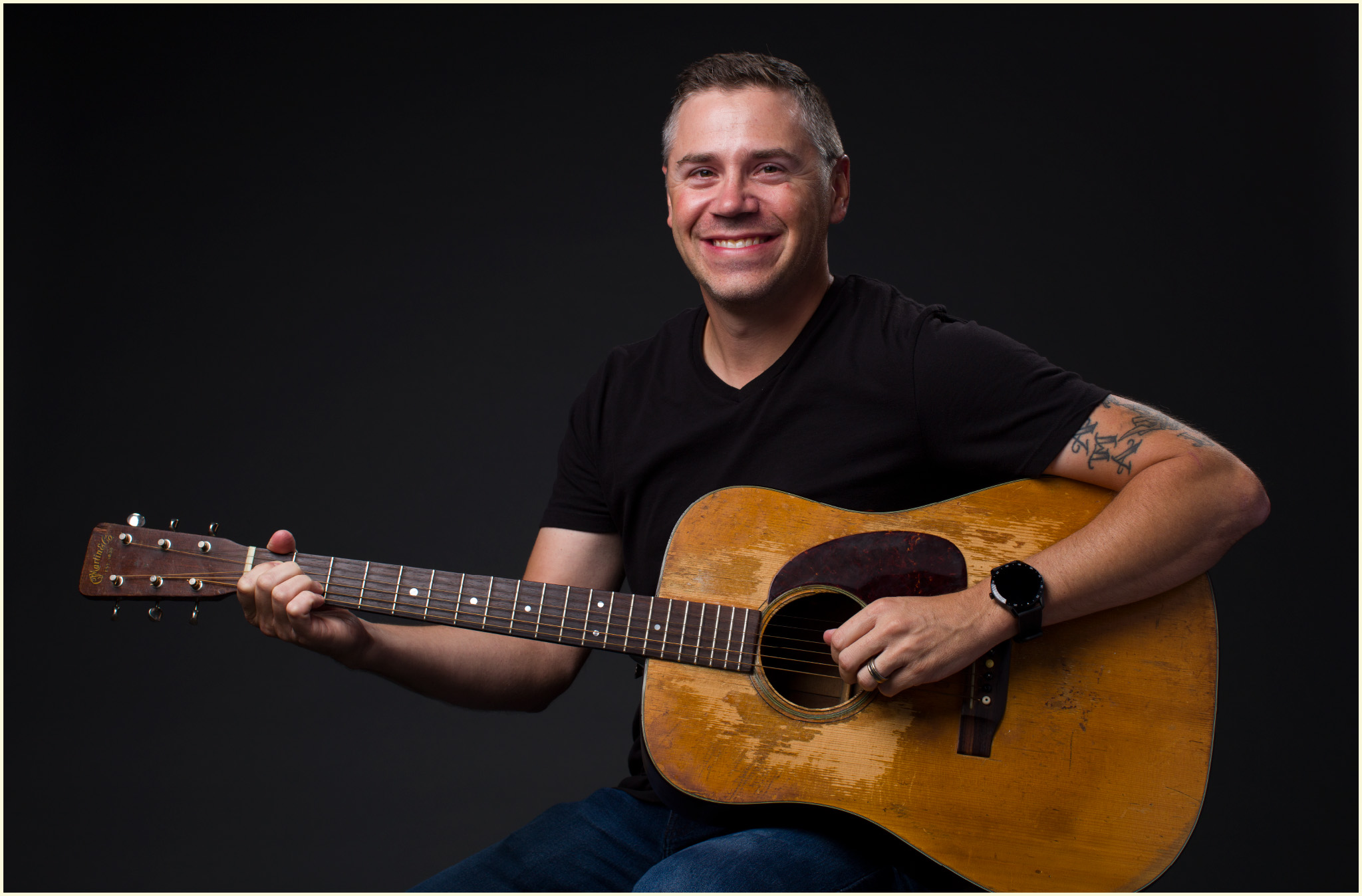 A photo of Jason Ahner holding a Martin guitar.