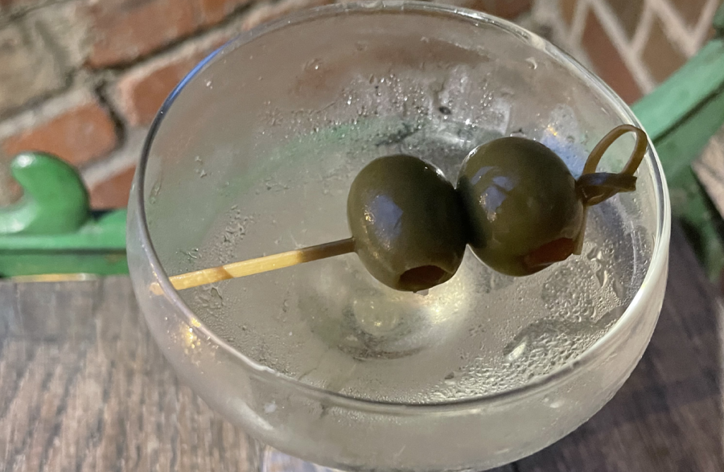 A close-up photo of a martini with two olives.