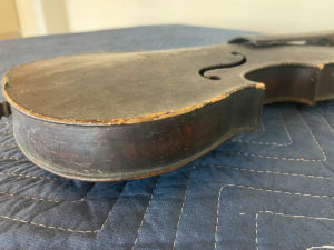 An old and worn fiddle seen in close up over the main body of the instrument.