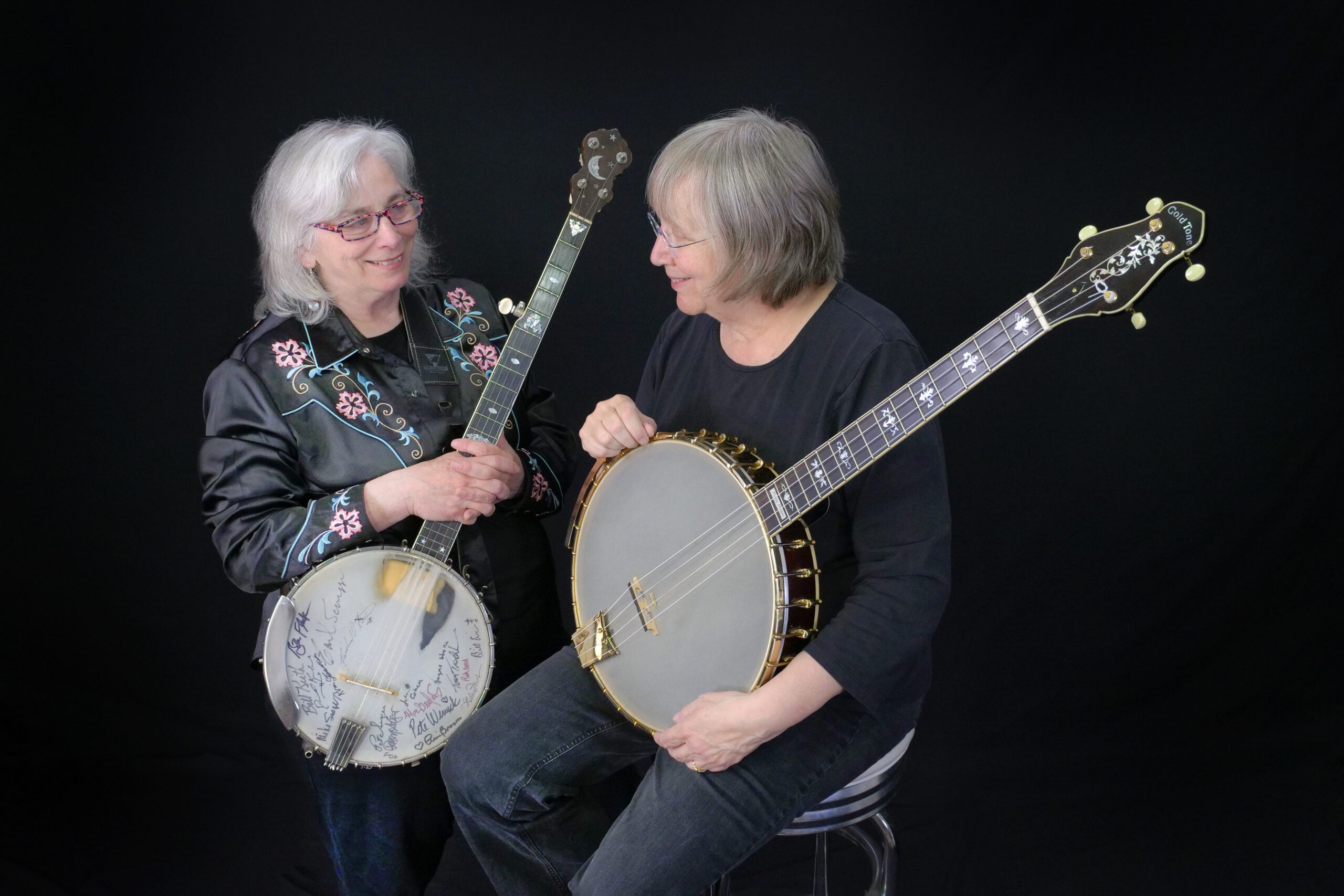 A photo of Cathy Fink and Marcy Marxer, each holding banjos.