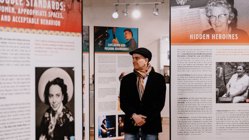 A photo of a man perusing the panels of the special exhibit "I've Endured: Women in Old-Time Music" at the Birthplace of Country Music Museum.
