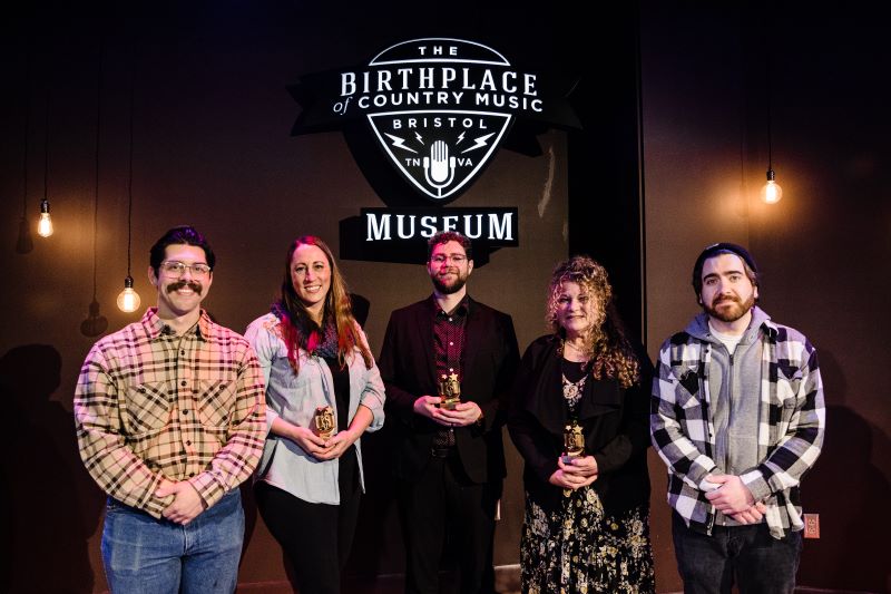 Roger Ramsey (alternate), Katie Powderly, Austin Barrett, Linda Mckenzie and Kevin Michael Duggan (alternate) photographed in front of the Birthplace of Country Music Museum sign inside the performance theater at the museum.