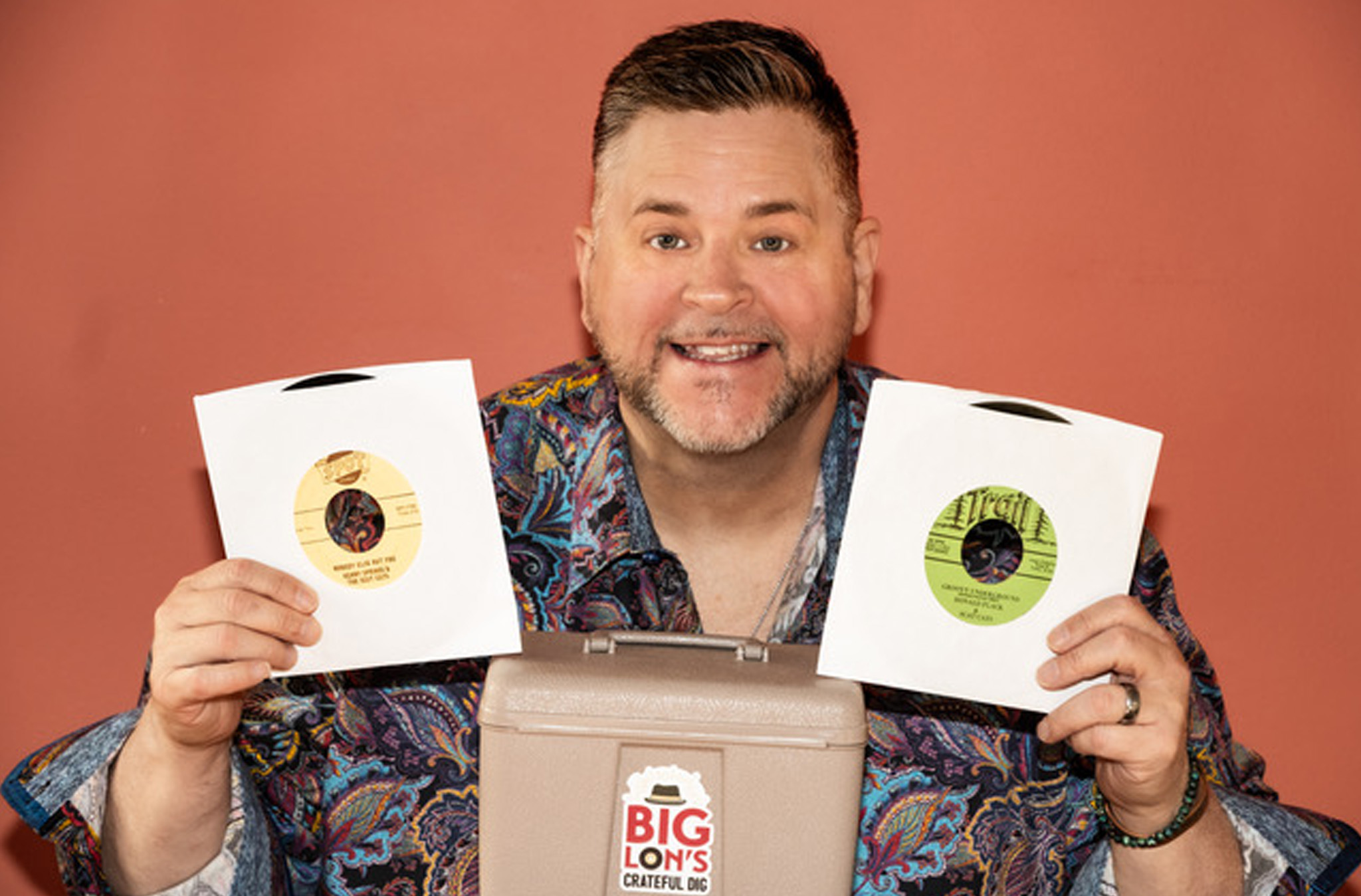 Photo of "Big Lon" holding up two 45 rpm records.