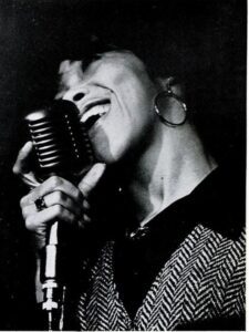 Up close image of Black woman singing into a mic.