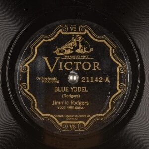 An old record with a weathered label depicting a dog listening to a phonograph over the word "Victor." Underneath, it reads "Blue Yodel" (Rodgers), Jimmie Rodgers, vocal with guitar.