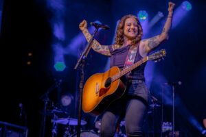 A photo of Ashley McBryde raising her arms in triumph from the State Street Stage at Bristol Rhythm & Roots Reunion.