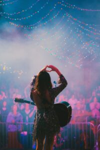 Molly Tuttle, photographed from behind, forms the symbol for love with her hands before an adoring crowd at the Cumberland Square Park Stage during Bristol Rhythm & Roots Reunion 2024.