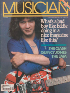 magazine cover with a young man with big wavy brown hair and an unbuttoned blue shirt. He is posed with his arms crossed and wearing a red guitar with whit and black stripes. 