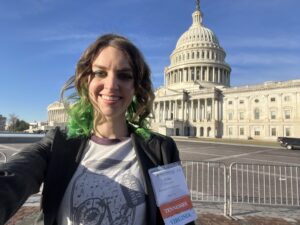 Young woman with green and brown hair taking a selfie in front of Capitol Hill